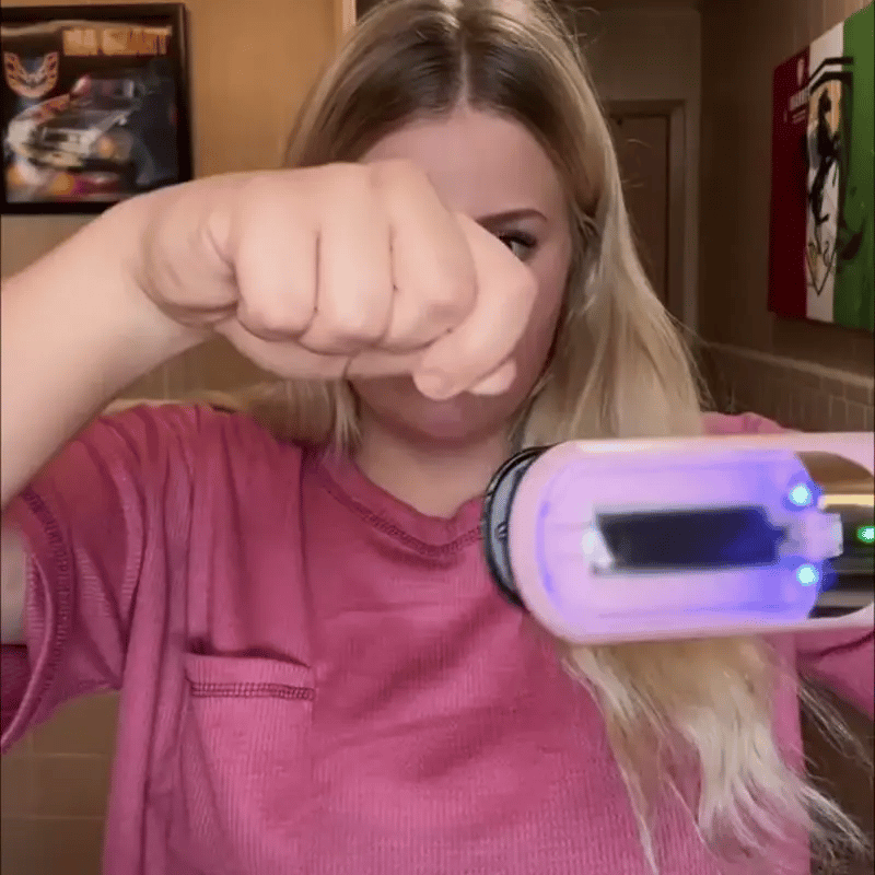 A woman holding the cordless trimmer up to a lifted section of her hair