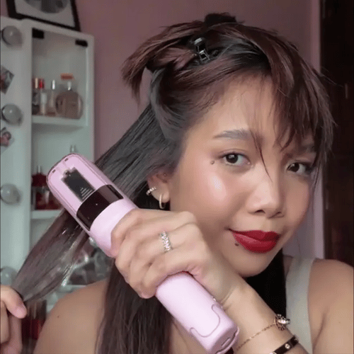 A woman gliding the trimmer down one smoothed section of her hair
